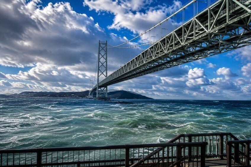 Un puente colgante sobre aguas turbulentas, con cielo despejado y tierra a lo lejos. 4