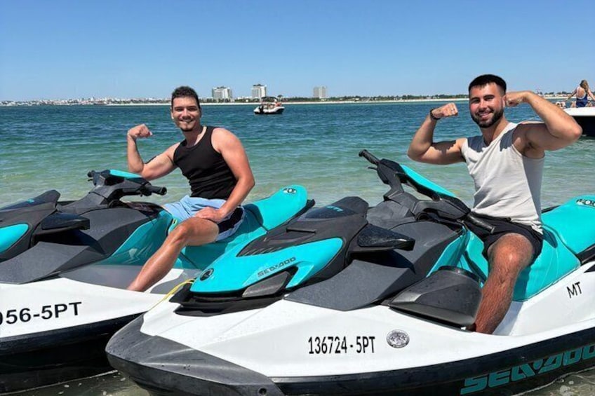 Two jet skis on a body of water with a distant shoreline and buildings. 1