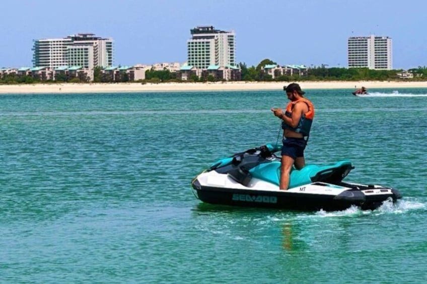 A person on a jet ski near a beach with buildings in the background. 4