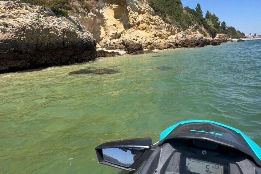 A body of water with a rocky shoreline and a jet ski in the foreground. 2