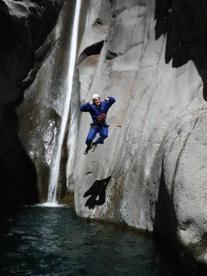 A person jumping off a cliff into a waterfall. 4