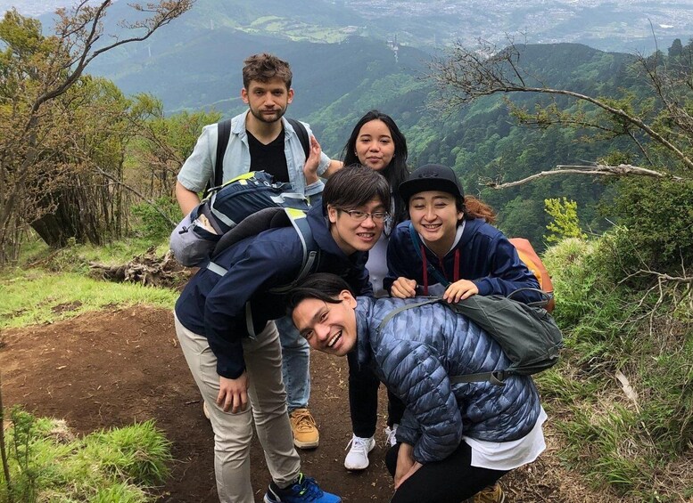 A group of people hiking on a mountain trail with a scenic view of a valley. 1