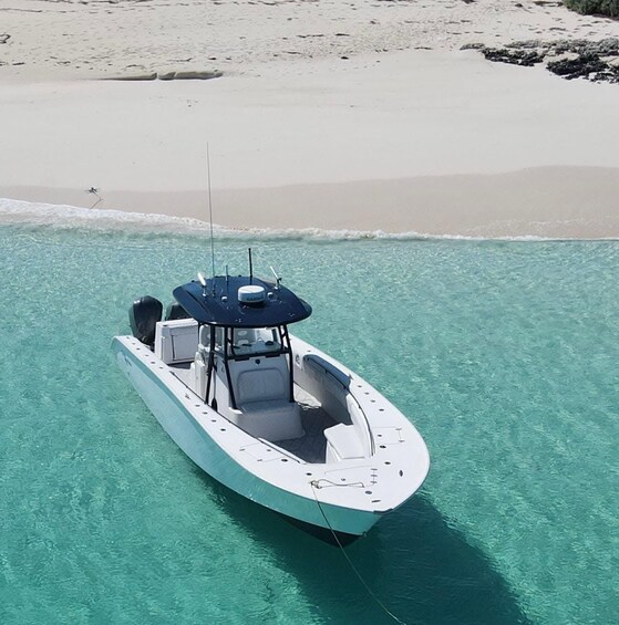 A boat anchored in clear turquoise water with a sandy beach in the background. 1