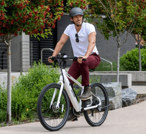 A person riding a white electric bicycle on a sidewalk. 3