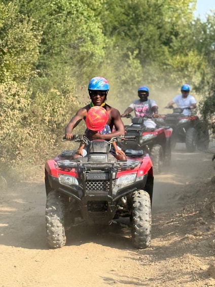 Three people riding ATVs on a dirt road surrounded by vegetation. 1