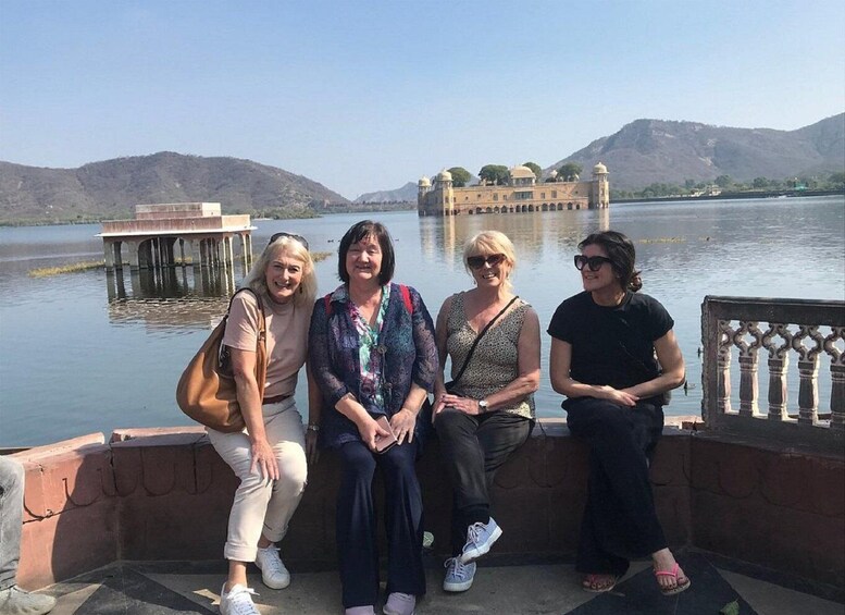 A group of people sitting by a lakeside with a palace in the background. 4