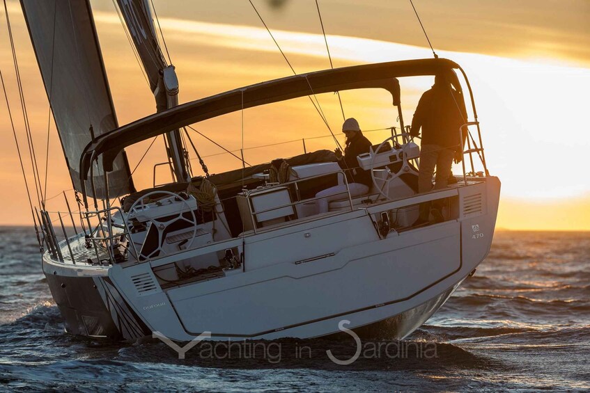 A sailboat with a person steering, on the water during sunset. 3