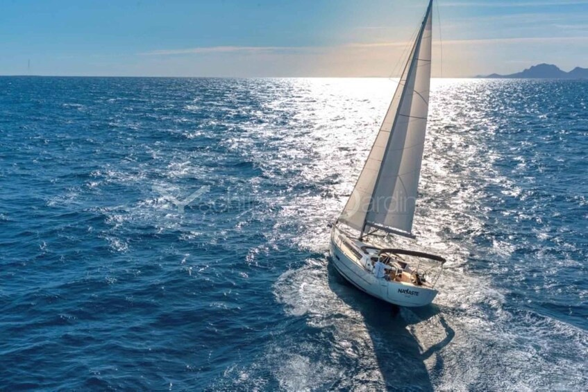 A sailboat on a calm sea with a clear sky and distant mountains. 2