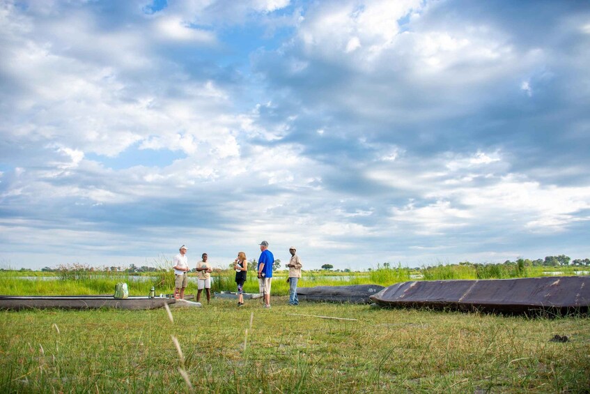 A group of people standing on a grassy field with a cloudy sky above. 2