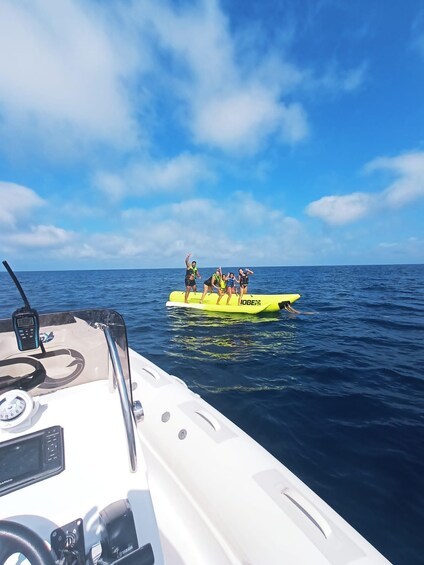 A boat with people on a yellow inflatable platform in the ocean. 1