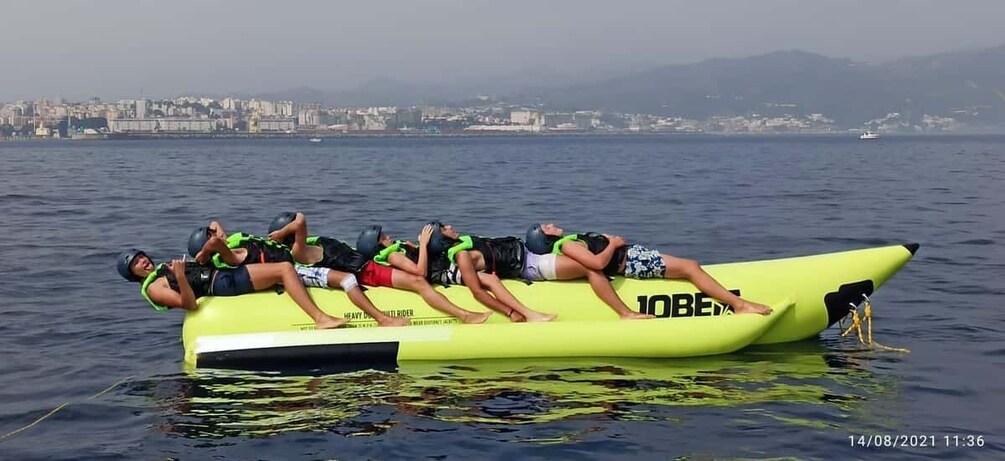 A group of people on a yellow inflatable raft in the water with a cityscape in the background. 3