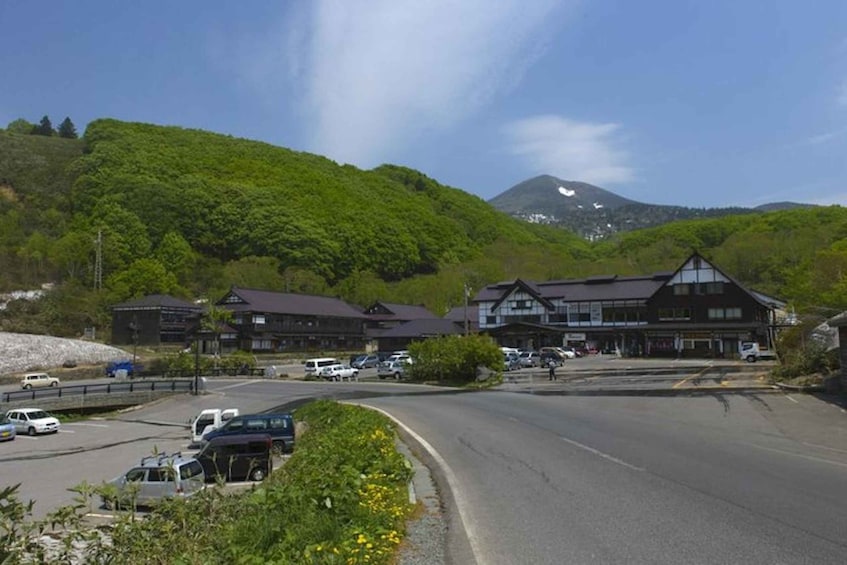 A mountain road with parked cars and a building with a dark roof. 4