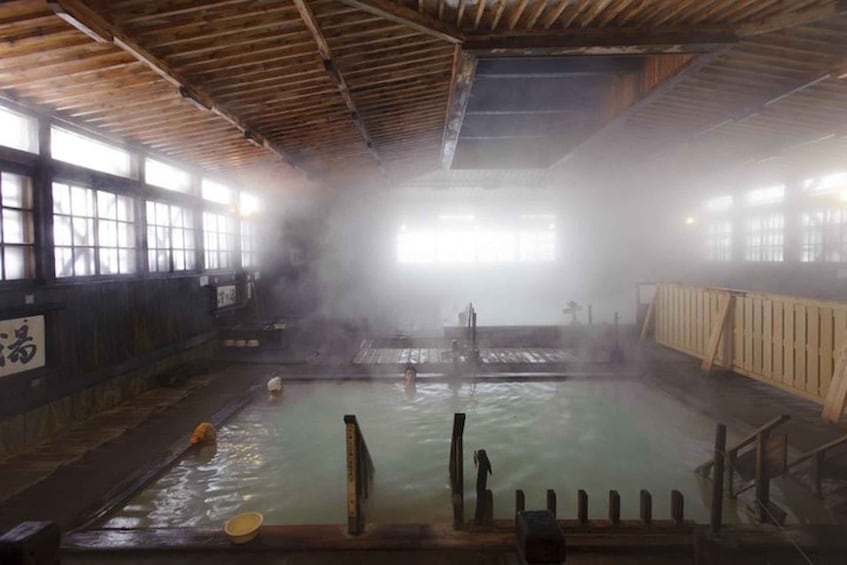 A traditional hot spring bath with wooden beams, tiled walls, and a misty atmosphere. 3