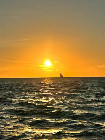Ein Sonnenuntergang über dem Meer mit einem Segelboot in der Ferne. 3