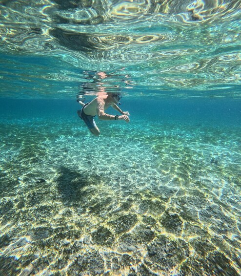 A person scuba diving underwater with clear visibility of the seabed. 5