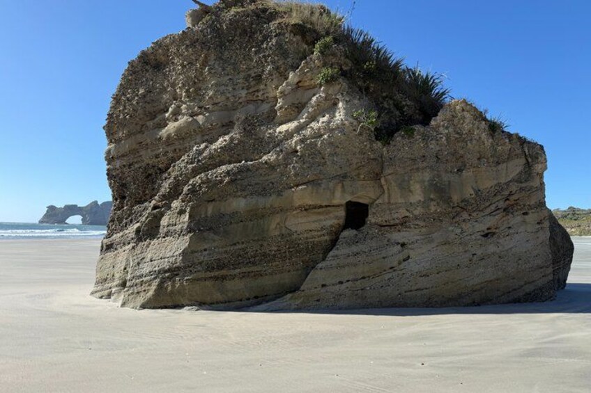 A large rock formation on a beach with a clear sky. 3