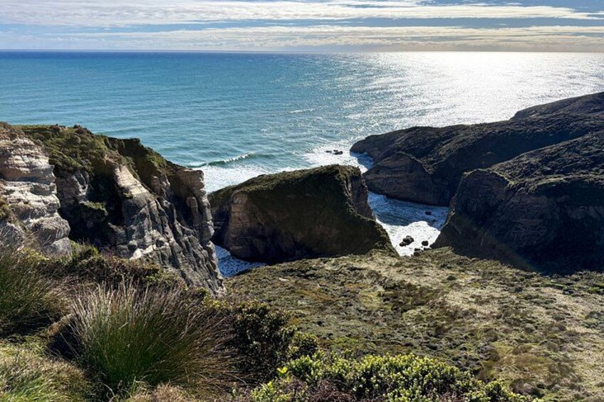 A coastal landscape with cliffs, a rocky shoreline, and a view of the ocean. 4