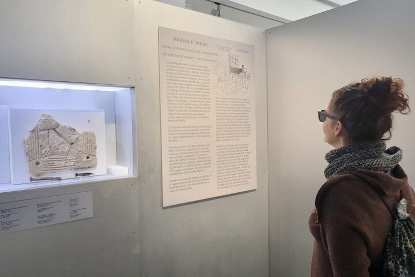 A person viewing an exhibit with a display case containing a model and a large informational poster. 4