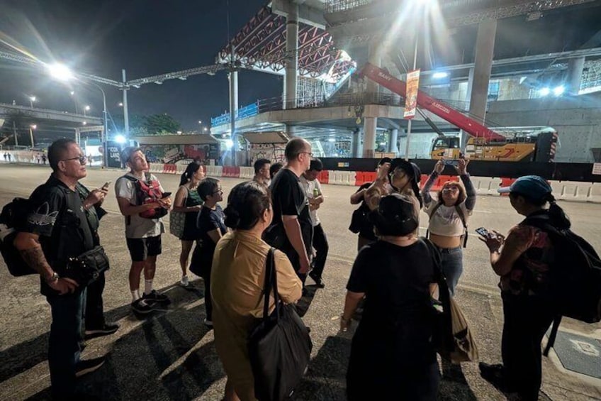 A group of people standing in a line at a sports event, with a large stadium structure in the background. 3