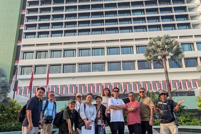 A group of people standing in front of a modern building with a palm tree. 5