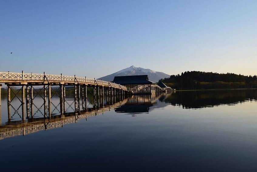 A bridge over a calm lake with a mountain in the background. 5
