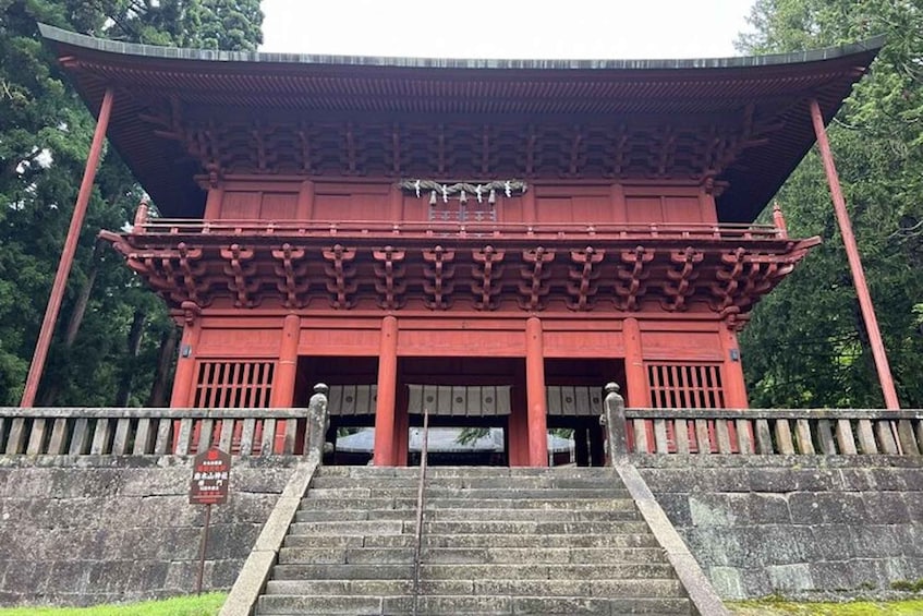 A traditional red building with a curved roof and a staircase leading up to the entrance. 3