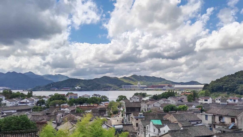 A coastal town with traditional buildings, a large body of water, and mountains in the background. 1