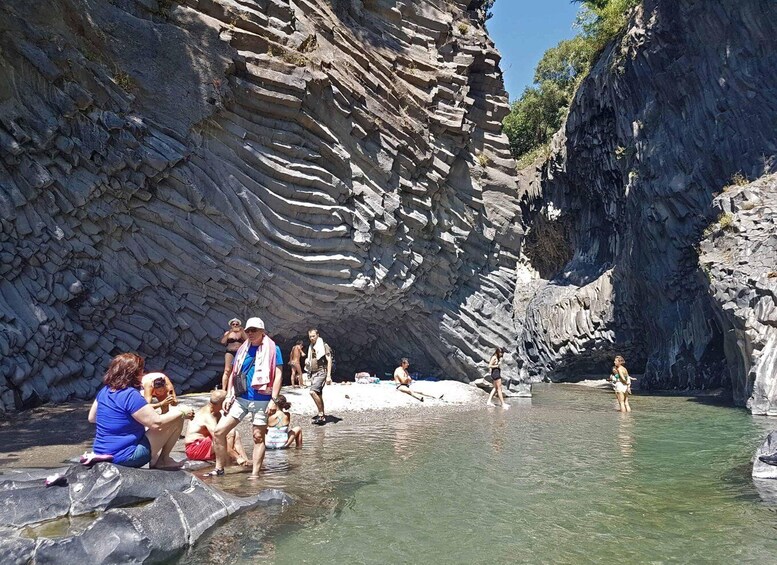 A group of people enjoying a natural hot spring surrounded by rocky cliffs. 3