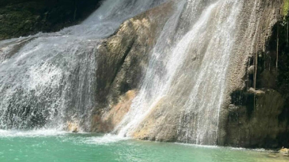 A waterfall cascading into clear turquoise water. 1