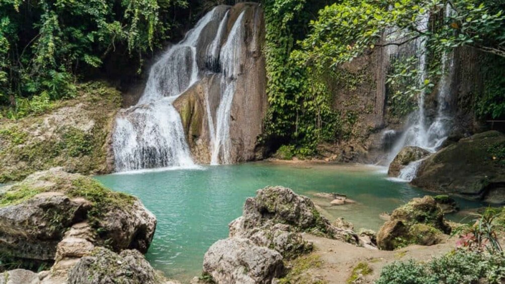 A waterfall cascading into a clear pool surrounded by rocks and greenery. 3