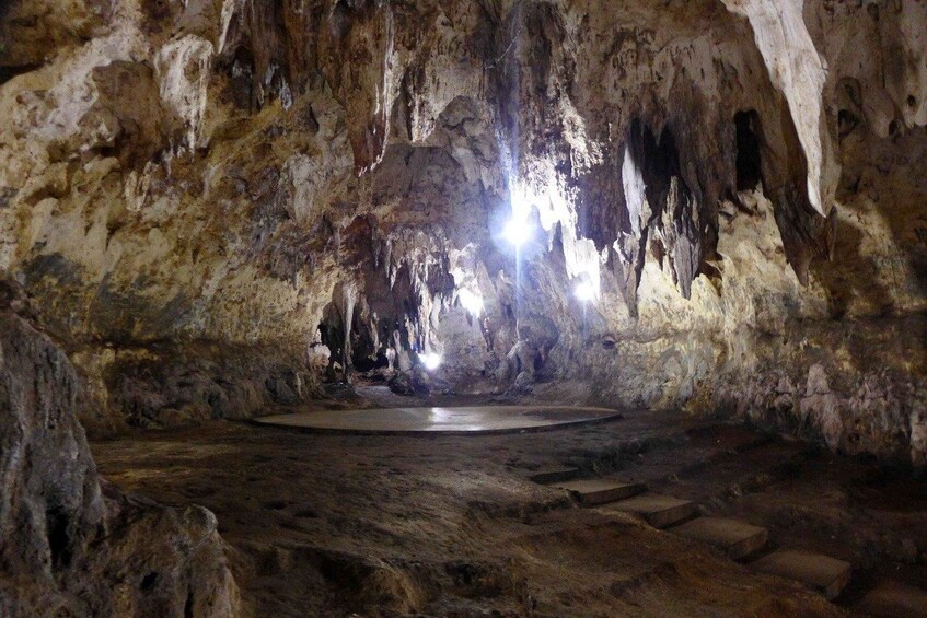 A cave with stalactites and stalagmites, a circular opening, and a stone floor. 2