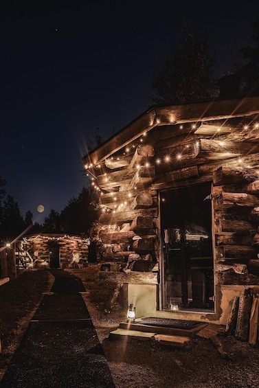 A rustic cabin at night with string lights and a full moon in the background. 4