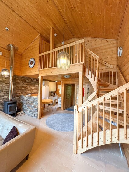 A wooden interior with a staircase, a stone wall, a fireplace, and a dining area. 5