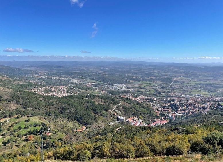 A panoramic view of a town nestled in a valley with surrounding hills and mountains. 1