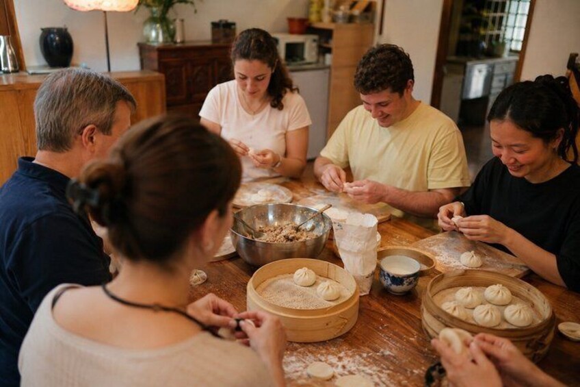 A group of people preparing food, with bowls of dough and ingredients on a table. 1