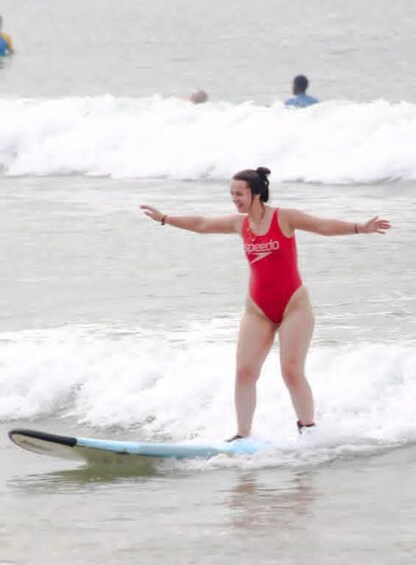 A person in a red swimsuit surfing on a wave. 5