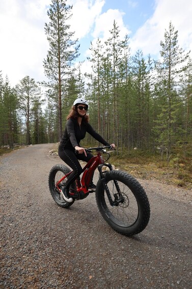 A person riding a mountain bike on a gravel path in a forested area. 1