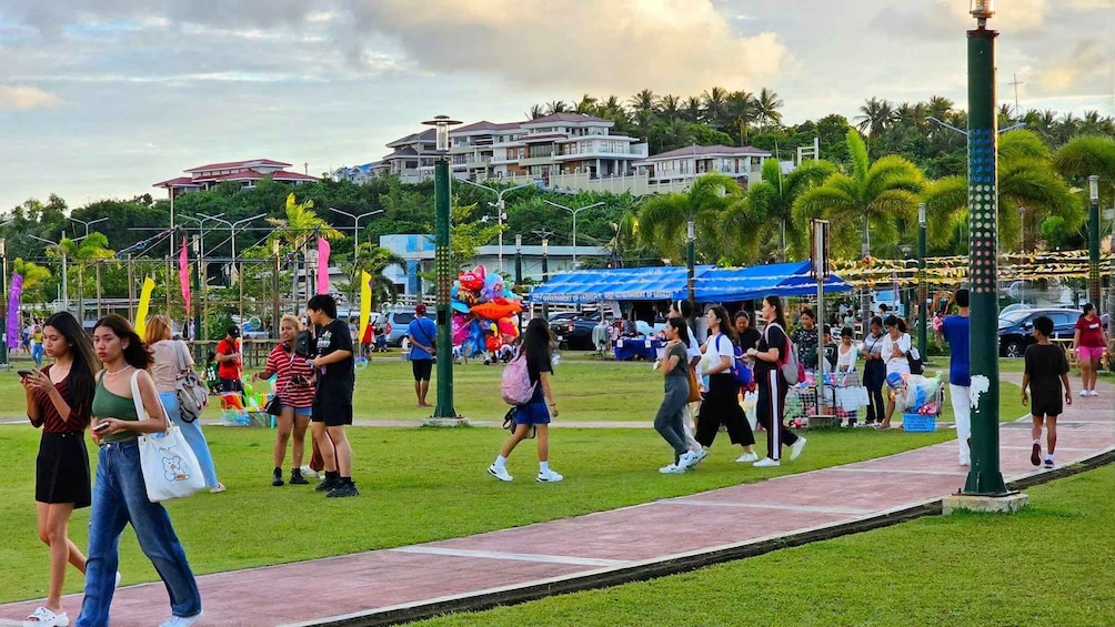 A park with people walking, a blue tent, and buildings in the background. 5
