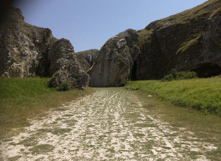 A dirt path leading through a rocky canyon with large boulders on either side. 3
