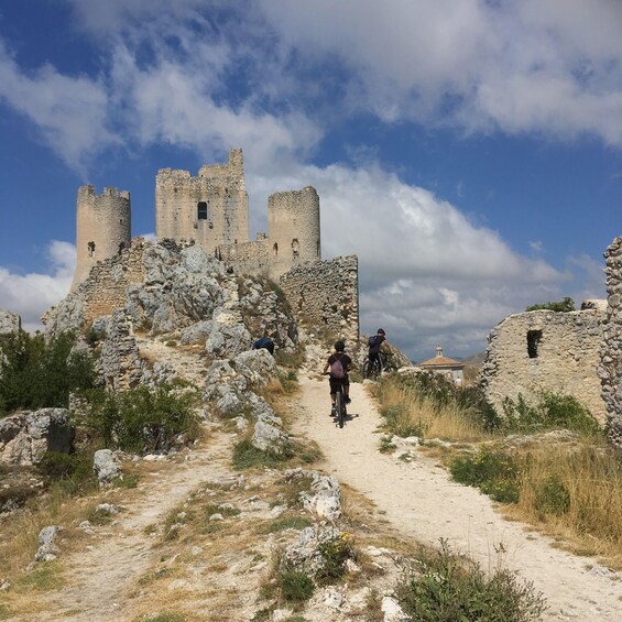 A dirt path leading to a historic stone castle with ruins. 1