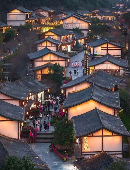 A traditional village with tiered buildings and a crowd gathering at the entrance. 2