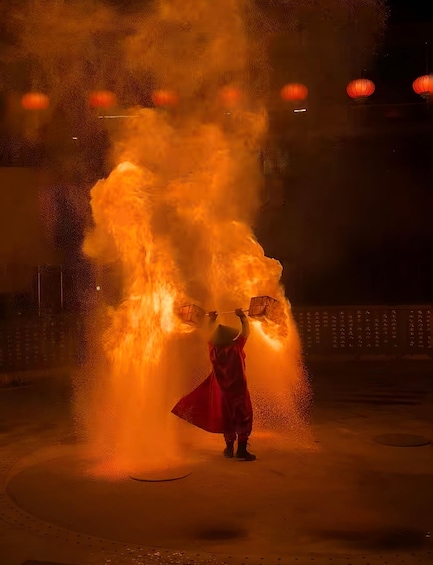 A person in a red dress performing a fire act with a large fireball. 1