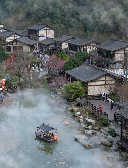 A traditional village with wooden houses, a river with a boat, and a misty forested hill in the background. 4