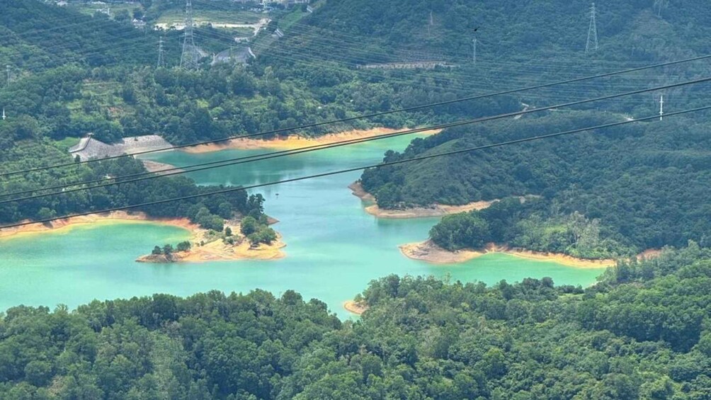 A coastal landscape with multiple small islands surrounded by turquoise waters, dense green forests, and power lines overhead. 2