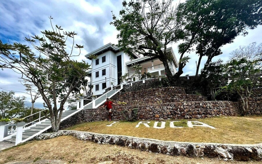 A stone staircase leading up to a white building with a person in a red shirt. 3