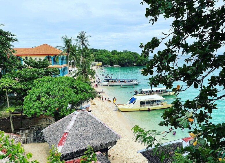 A beach with boats, people, and buildings. 1