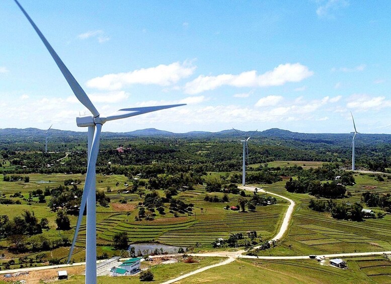 A landscape with multiple wind turbines, a winding road, and a green valley with scattered buildings. 2