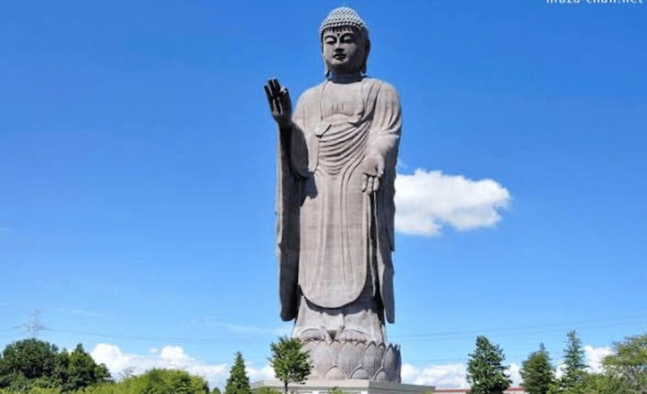 A large Buddha statue with a raised hand, set against a clear blue sky. 1