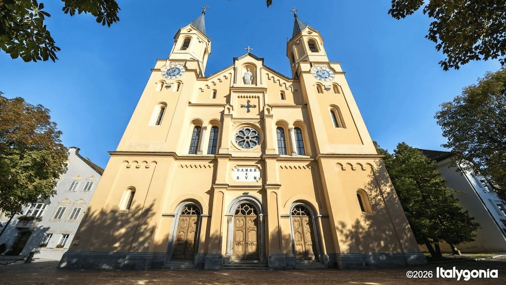 A large church with two towers, a central clock, and a statue in front. 3