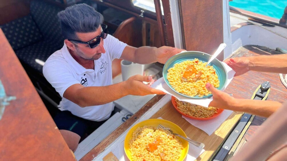 A person serving food from a pot to another person at a wooden table on a boat. 5